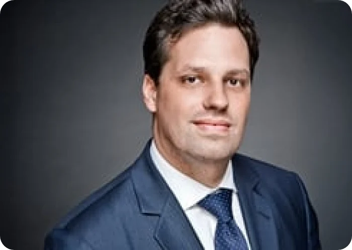 Porträt von Dr. Christian Pfeifer in einem Anzug mit Krawatte vor neutralem Hintergrund.