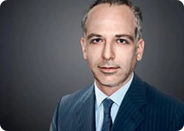 Porträt von Marcello Fedele in einem gestreiften Anzug mit Krawatte vor einem neutralen Hintergrund.