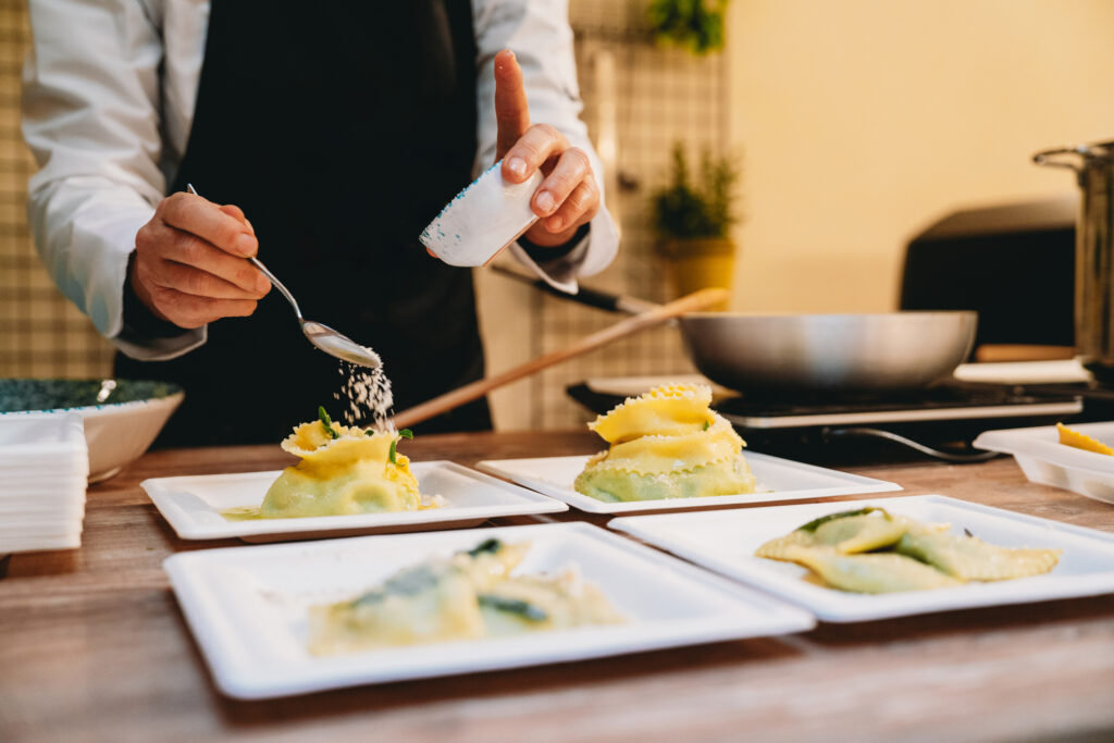 Ein Koch, der ein Nudelgericht in einem Restaurant verfeinert.